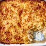 A baked chicken hashbrown casserole with a golden cheese crust in a white dish.