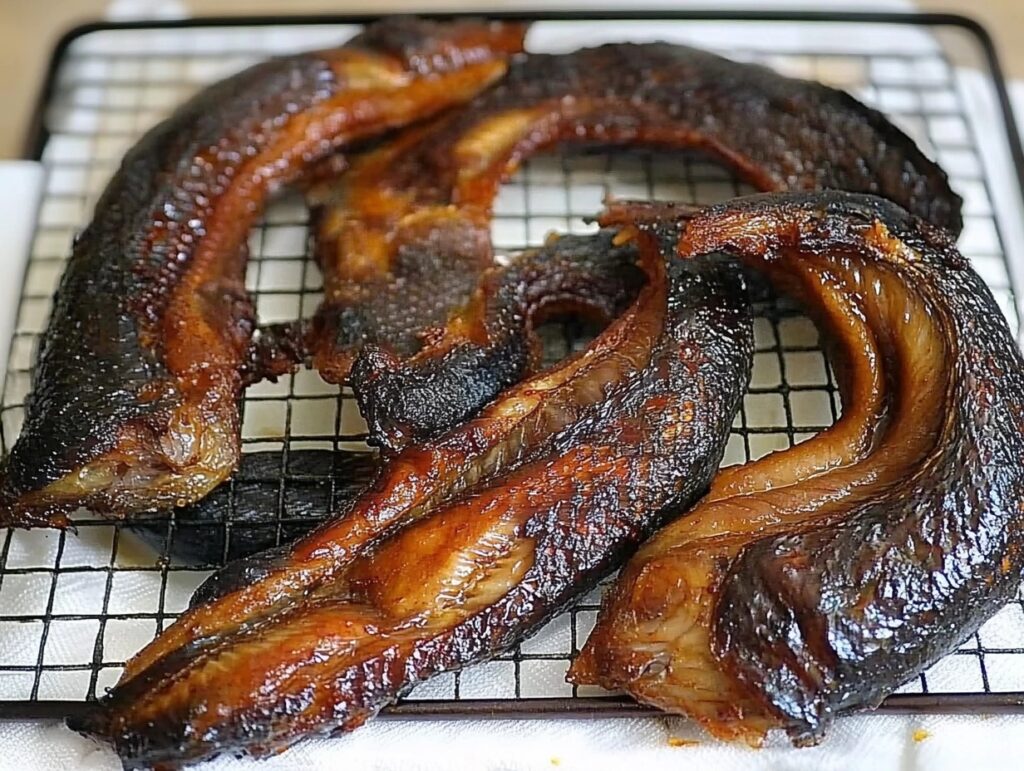 Golden-brown smoked catfish fillets resting on a cooling rack.